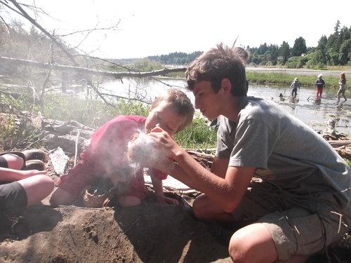 Youth learn to make friction fire with sticks in a Nature Studies program.